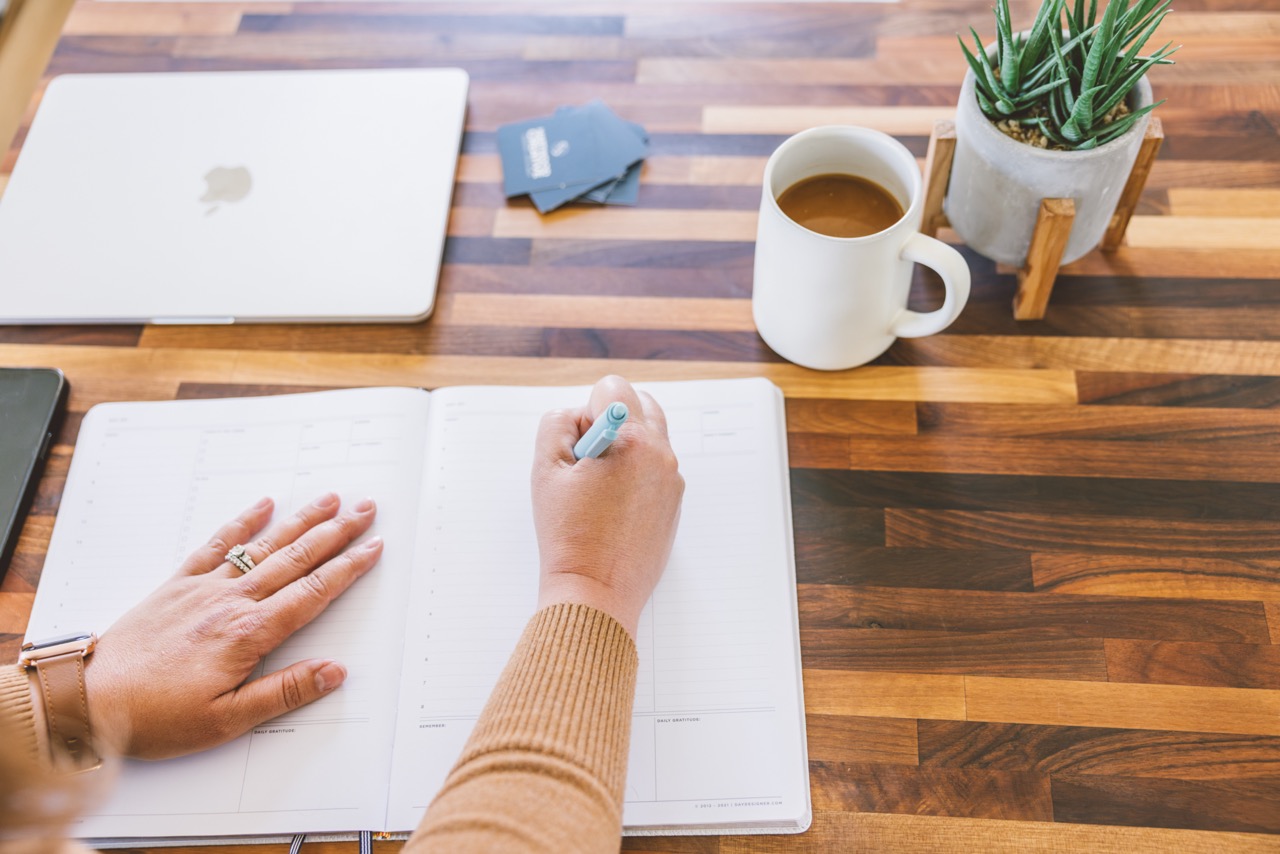 woman writing in a planner at a desk